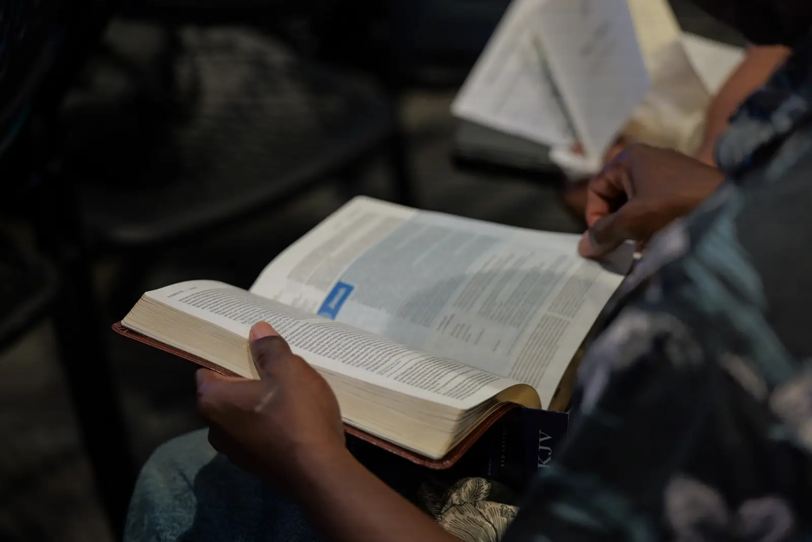 Hands holding an open Bible during a service at Huikala