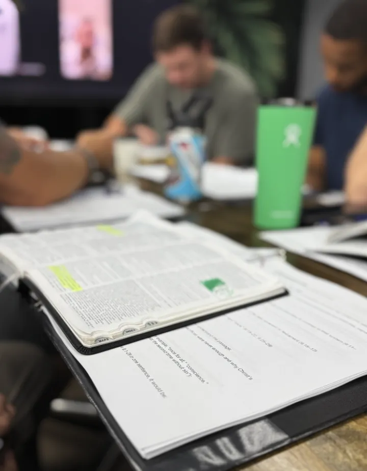 An open Bible and study notes beside a water bottle