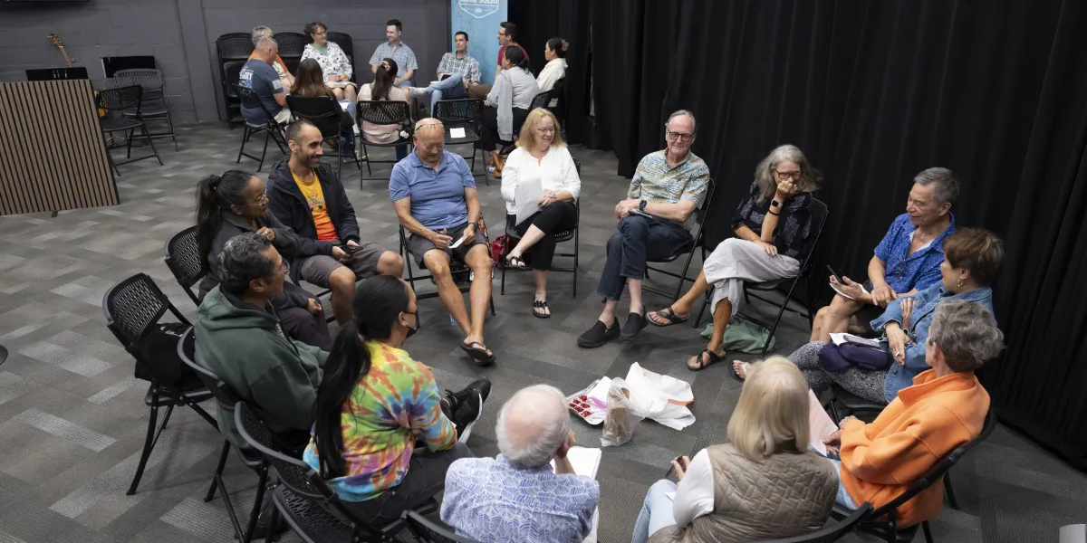 A small group sitting in a circle with their study sheets, another group meeting behind them